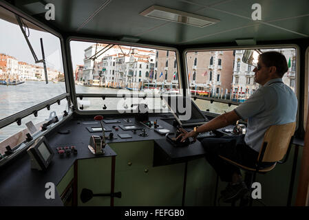 Ein Besatzungsmitglied an der Steuerung des ACTV Vaporetto (Wasserbus), der auf dem Canal Grande (Canal Grande) in Venedig, Italien, fährt. Das Vaporetto ist ein Stockfoto