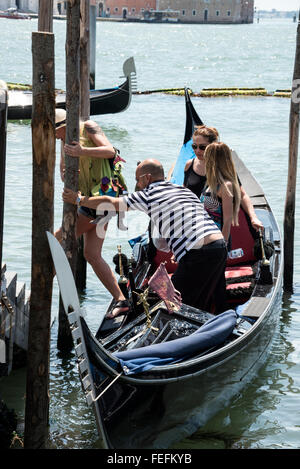 Eine Gruppe junger Touristen steigt aus einer Gondel auf der Lagune von Venedig in der Nähe des Markusplatzes in Venedig aus. Stockfoto