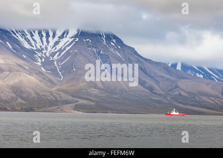 Schöner Ausblick mit Norge cruise Boot angedockt in Longyearbyen Hafen vor dem Hintergrund der beschlagene schwarzen Berg und cal Stockfoto