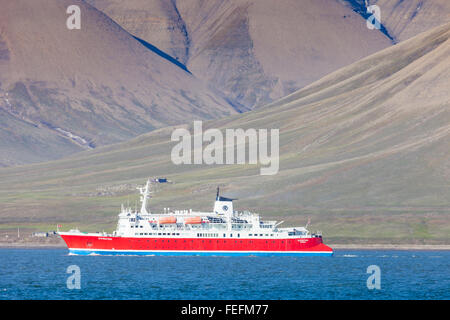 Schöner Ausblick mit Norge cruise Boot angedockt in Longyearbyen Hafen vor dem Hintergrund der beschlagene schwarzen Berg und cal Stockfoto