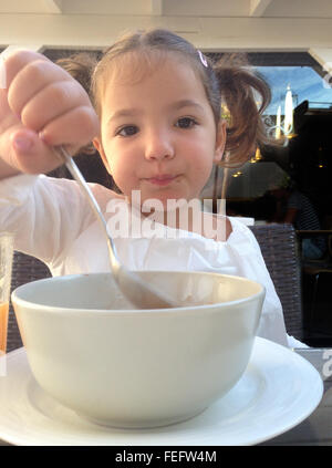 Kind Mädchen mit einem gesunden Frühstück im Freien. Sie isst Schokolade Flocken und Orangensaft Stockfoto