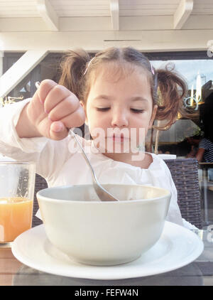 Kind Mädchen mit einem gesunden Frühstück im Freien. Sie isst Schokolade Flocken und Orangensaft Stockfoto