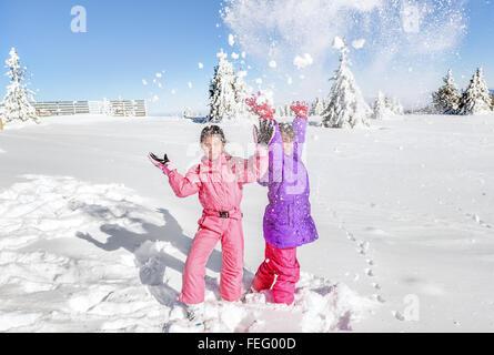 Zwei kleine Mädchen spielen mit Schnee und Spaß Stockfoto