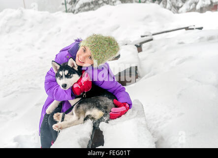 Glückliches kleines Mädchen hält ihr Welpe Hund husky auf dem Schnee Stockfoto