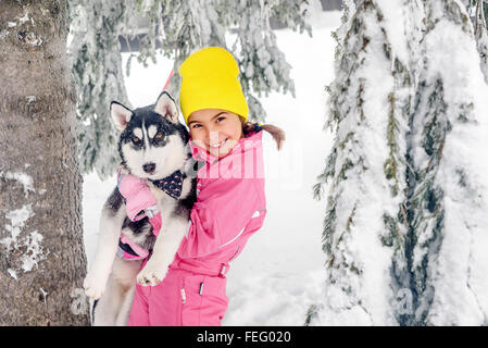 Kleine Mädchen spielen mit Husky Hund im Schnee Stockfoto