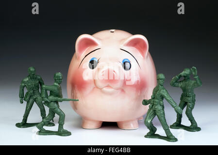 Amerikanisches Geld in das Sparschwein mit grünen Spielzeugsoldaten zu schützen. Stockfoto