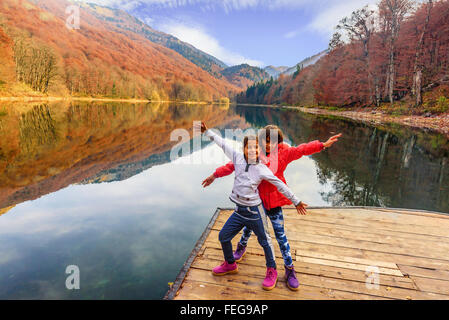 Zwei glückliche kleine Mädchen stehen auf dem Pier von See Biograd (Fischernächte Jezero), Biogradska Gora Nationalpark im Herbst, Monte Stockfoto