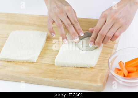 Brot schneiden in Kreisform auf weißen Teller mit Frauen Hände im Hintergrund arbeiten. Stockfoto