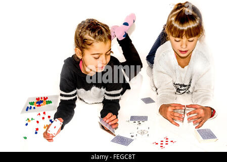 Glückliche kleine Mädchen machen Kartenhaus isoliert auf weiss Stockfoto
