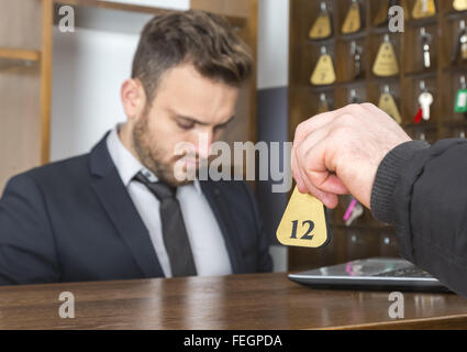 Bild eines Gastes Aushaendigen des Schlüssels an der Rezeption des Hotels. Selektiven Fokus auf dem Schlüssel. Stockfoto