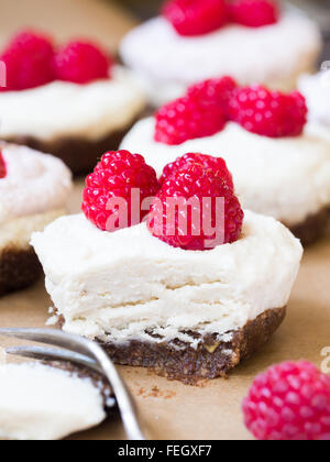 Vegane Mini "Käsekuchen" vorgenommen von Cashew-Nüssen, Kokos-Creme und Datumsangaben, serviert mit Himbeeren. Hautnah. Stockfoto