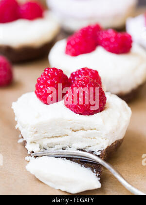 Vegane Mini "Käsekuchen" vorgenommen von Cashew-Nüssen, Kokos-Creme und Datumsangaben, serviert mit Himbeeren. Hautnah. Stockfoto