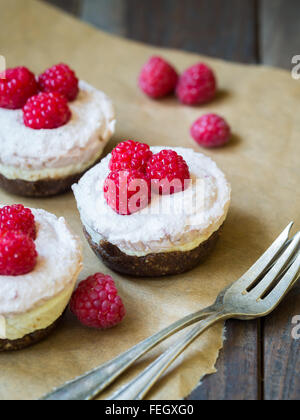 Vegane Mini drei Farben "Käsekuchen" vorgenommen von Cashew-Nüssen, Kokos-Creme und Datumsangaben, serviert mit Himbeeren. Stockfoto