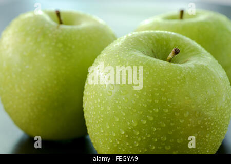Grüner Apfel mit Tröpfchen auf schwarzem Hintergrund Stockfoto