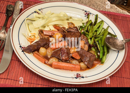 Teller mit Herz Bier Bourguignon mit Nudeln und Bohnen Stockfoto