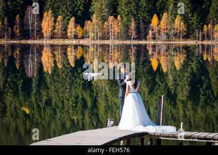 Bräutigam und Braut, gefilmt von einer Drohne am Ufer eines Sees in einem herbstlichen Ambiente Stockfoto