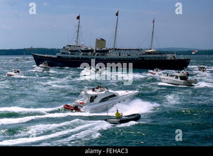 AJAXNETPHOTO - JUNI 1994. SPITHEAD, ENGLAND. -KÖNIGIN BEWERTUNGEN D-DAY JUBILÄUM FLOTTE - DIE ROYAL YACHT BRITANNIA TRAGEN H.M DIE KÖNIGIN, BEGINNT DIE ÜBERPRÜFUNG DER DIE FLOTTE, GEFOLGT VON EINE FLOTTILLE VON SPORTBOOTEN. FOTO; JONATHAN EASTLAND/AJAX REF: 402822 Stockfoto