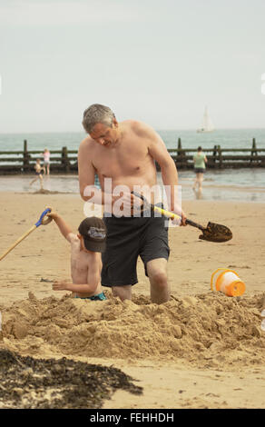 Vater und Sohn genießen, Sandburgen an einem heißen Augusttag am Walton auf ganz blöd, Essex, England. Stockfoto