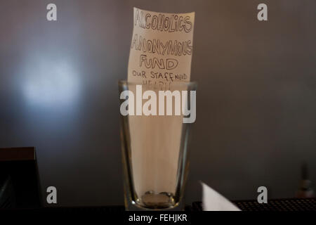 "Alkoholiker anonyme Fonds" geschrieben auf Papier innen Tip Jar auf Bar in London Veranstaltungsort. Stockfoto