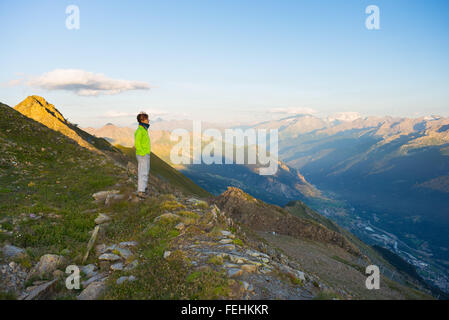 Frau atemberaubenden Sonnenaufgang über Täler, Grate und Gipfel zu beobachten. Weitwinkelaufnahme aus 3000 m im Valle d ' Aosta. Sommer-Anzeige Stockfoto