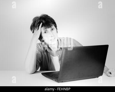 Applying Frau mit Laptop, müde. Retro gefiltert monochromes Bild. Stockfoto