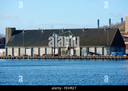 Karlshamn, Schweden - 4. Februar 2016: Ein Industriegebiet im Hafen von Karlshamn. Hier ist eine alte Lagerhalle mit einem cra Stockfoto