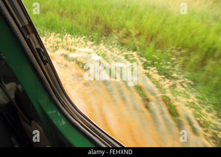 Blick aus dem Fenster als Safari-LKW fährt durch eine Pfütze, erstellen einen Spritzer Stockfoto