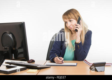 Junge Frau Sekretärin sitzt am Schreibtisch arbeiten, isoliert auf weißem Hintergrund Stockfoto