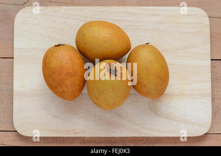 Ganze und teilweise frisch Sapodilla auf einem Holzbrett. Stockfoto