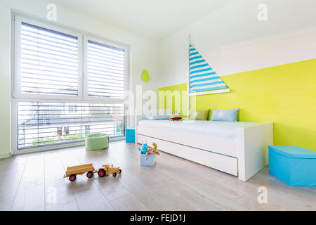 Im Kinderspielzimmer mit einem Bett ein großes Fenster anzeigen Stockfoto