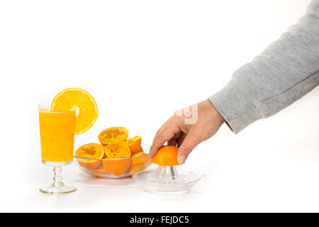 Hand presst Orangensaft aus Glas mit Orangen Stockfoto