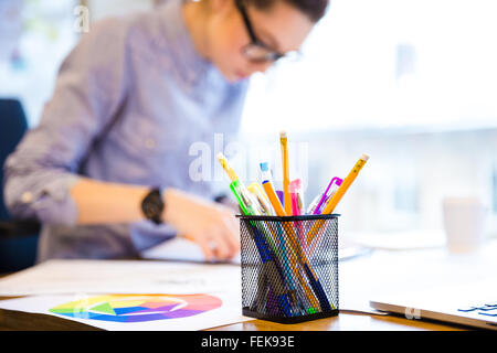 Ernste junge weibliche Mode-Designer in Gläsern im Büro sitzen und Skizzen Stockfoto