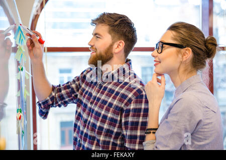 Junge Unternehmer und Unternehmerin mit Whiteboard im Büro arbeiten Stockfoto