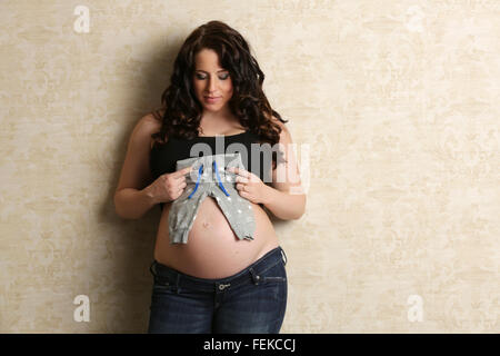 Schwangere Frau mit Babyhwollhose Stockfoto