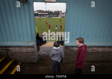 Zwei jungen Zuschauern die erste Halbzeit-Aktion als Port Talbot Town (in blau) im Genquip-Stadion, früher bekannt als Victoria Road Gastgeber Caerau Ely Welsh Cup vierten Runde unentschieden spielen. 1901 als Port Talbot Athletic von im Exil lebenden Schotten gegründet, startete sie im lokalen und regionalen Fußball vor gefördert, die League of Wales im Jahr 2000 und ändern ihren Namen auf die aktuelle Version ein Jahr später. Stadt diese Krawatte 3: 0 gegen ihre Gegner aus der walisischen Liga gewonnen, beobachtet eine Ebene unterhalb der walisischen Premier League, wo Port Talbot konkurrierten, von einer Schar von 113. Stockfoto