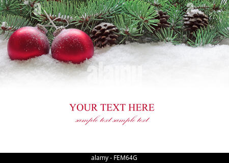 Rote Weihnachtskugeln und Zweig der Tanne im Schnee auf dem weißen Hintergrund isoliert. Stockfoto