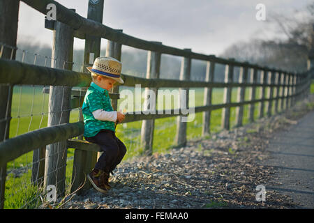 Kleiner Junge sitzt auf einem Stil im Frühjahr Stockfoto