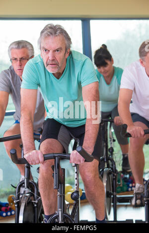 Eine Gruppe von Senioren, die mit Hilfe der Spinning-Bikes in der Turnhalle Stockfoto