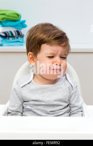 Schließen Sie herauf Bild eines verärgert Babys in seinem Hochstuhl. Stockfoto