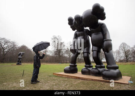 Wakefield, Yorkshire, Großbritannien. 8. Februar 2016. Ein Arbeiter sieht eine Skulptur mit dem Titel "Auf dem Weg" des amerikanischen Künstlers Brian Donnelly / KAWS, im nassen und windigen Zustand, zur Yorkshire Sculpture Park, in der Nähe von Wakefield, West Yorkshire, am 8. Februar 2016. Bildnachweis: Harry Whitehead/Alamy Live-Nachrichten Stockfoto