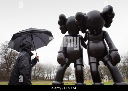 Wakefield, Yorkshire, Großbritannien. 8. Februar 2016. Ein Arbeiter sieht eine Skulptur mit dem Titel "Auf dem Weg" des amerikanischen Künstlers Brian Donnelly / KAWS, im nassen und windigen Zustand, zur Yorkshire Sculpture Park, in der Nähe von Wakefield, West Yorkshire, am 8. Februar 2016. Bildnachweis: Harry Whitehead/Alamy Live-Nachrichten Stockfoto