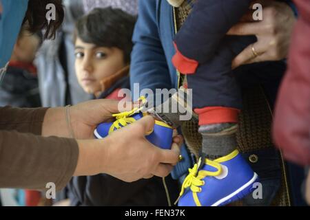 (160208)--GEVGELIJA, 8. Februar 2016 (Xinhua)--Mitarbeiter des UNHCR setzt auf neue Schuhe für ein Kind in einem Flüchtlingslager in Gevgelija, mazedonische Süd Grenze zu Griechenland am 7. Februar 2016.  Mehr als tausend Migranten gehen über Mazedoniens Grenze jeden Tag, die meisten davon aus Syrien, Afghanistan und Irak sind. Mit der Unterstützung von UNHCR, die mazedonische Regierung und NGOs, unterstützen die Flüchtlingslager völlig kostenlos alles, was die Migranten Transit in Mazedonien, durch die Bereitstellung von Schlafmatten, decken, Zelte und Unterkunft Hallen, Nahrung, Getränke, WIFI, medizinische Betreuung, Hygieneartikel, sowie Beratung, counsellin Stockfoto