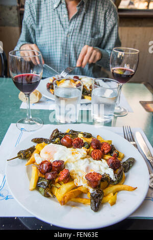 Spiegeleier mit Pommes frites, Chorizo und Padron Paprika in einem Restaurant. Stockfoto