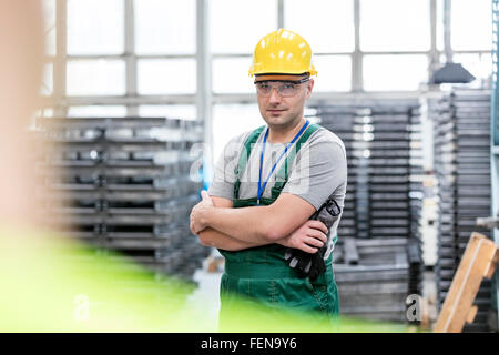 Porträt zuversichtlich Arbeiter mit verschränkten in Fabrik Stockfoto