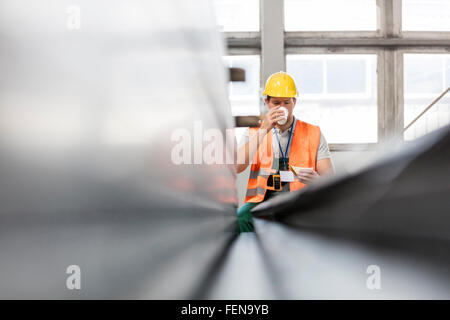 Arbeiter in Schutzkleidung Kaffeetrinken in Fabrik Stockfoto