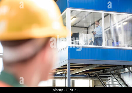 Arbeitnehmer, die betrachten Geschäftsmann in Fabrik-Büro Stockfoto