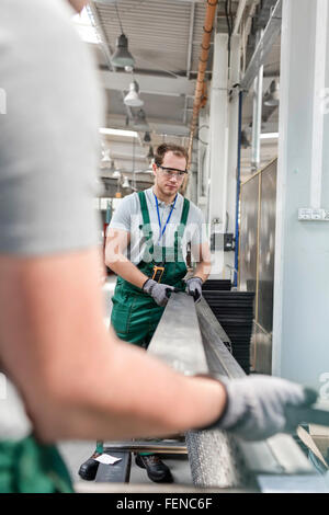 Arbeitnehmer, die Aufhebung von Metallteilen in Fabrik Stockfoto