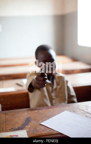 Mali, Afrika - August 2009 - Closeup Portrait eines schwarzen afrikanischen Grundschule Studenten zeigen eine Spielzeugpistole in Richtung der Kamera Stockfoto