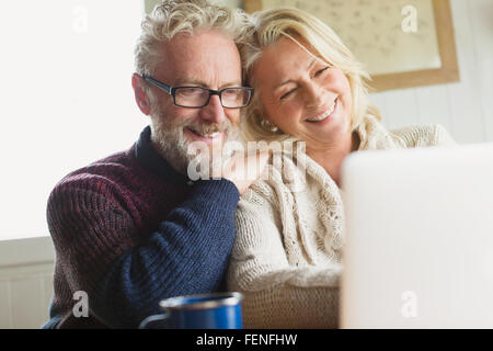 Lächelnde älteres Paar mit Laptop in der Küche Stockfoto