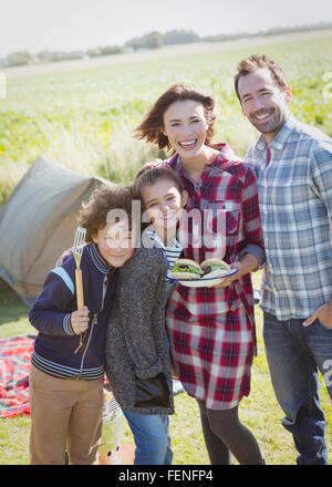 Porträt, Lächeln Familie mit gegrillten Hamburgern auf sonniger Campingplatz Stockfoto